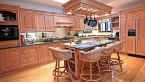 Una cocina amplia con armarios de madera, una isla central con taburetes y electrodomésticos modernos.