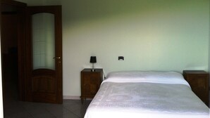 Ein Schlafzimmer mit Bett, Nachttisch, Lampe und Tür.