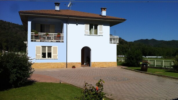 Ein zweistöckiges Haus mit Balkon, Schornstein und befestigter Auffahrt.