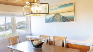A dining area with a wooden table, chairs, and a chandelier. -  Summer in Vilano Beach, St. Augustine with awesome Sunsets (St. Augustine)
