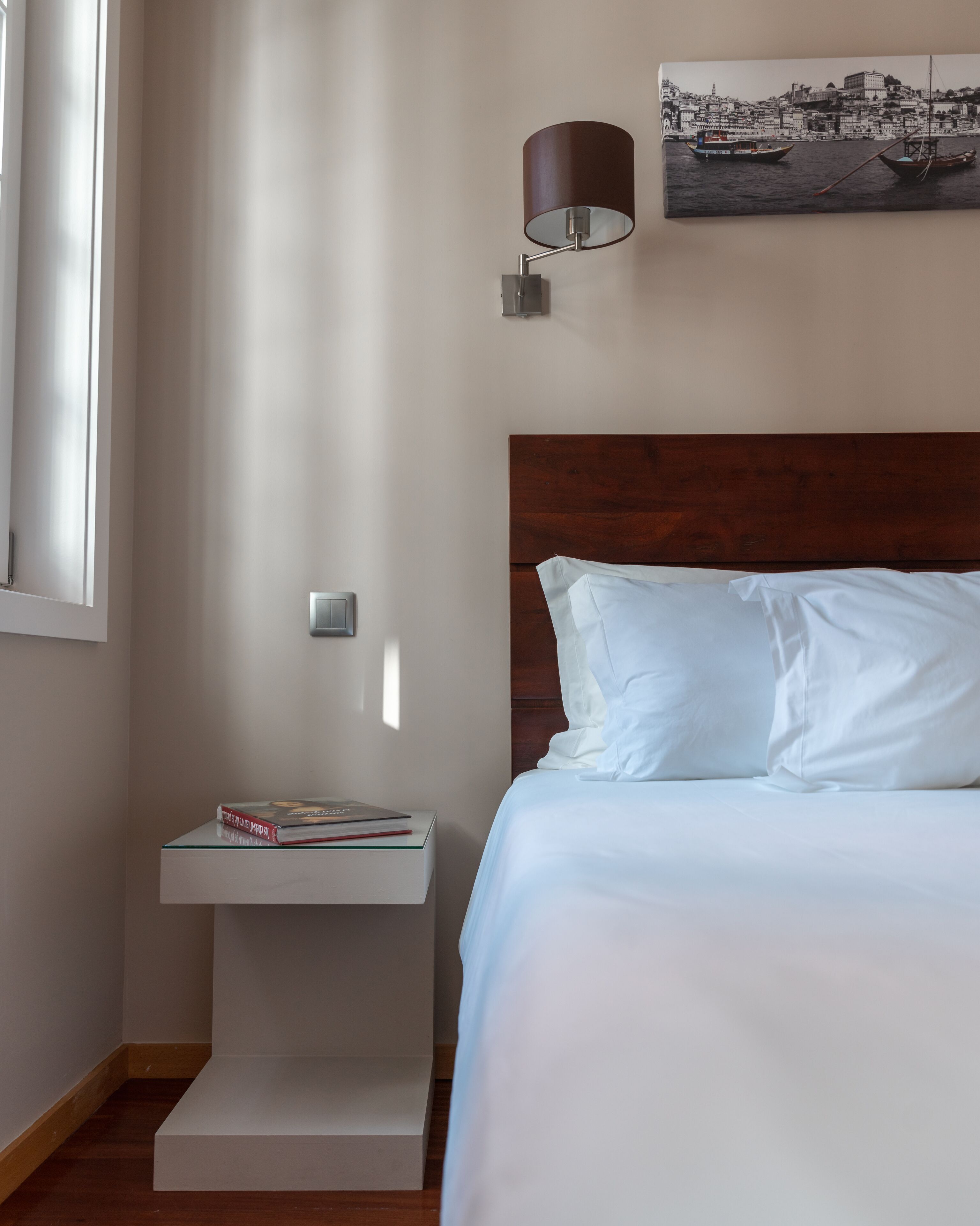 Un dormitorio con cabecera de madera, una mesita de noche con lámpara y un cuadro en la pared.