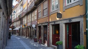 A narrow cobblestone street lined with historic buildings, including a hotel with a red door and a sign indicating it is the 'GUEST HOUSE DOURO'. - Guest House Douro (Porto)