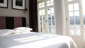 A hotel room with a bed, a large window, and a view of a cityscape. - Guest House Douro (Porto)