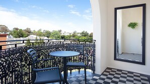 A balcony with a checkered floor, a round table, and two chairs.