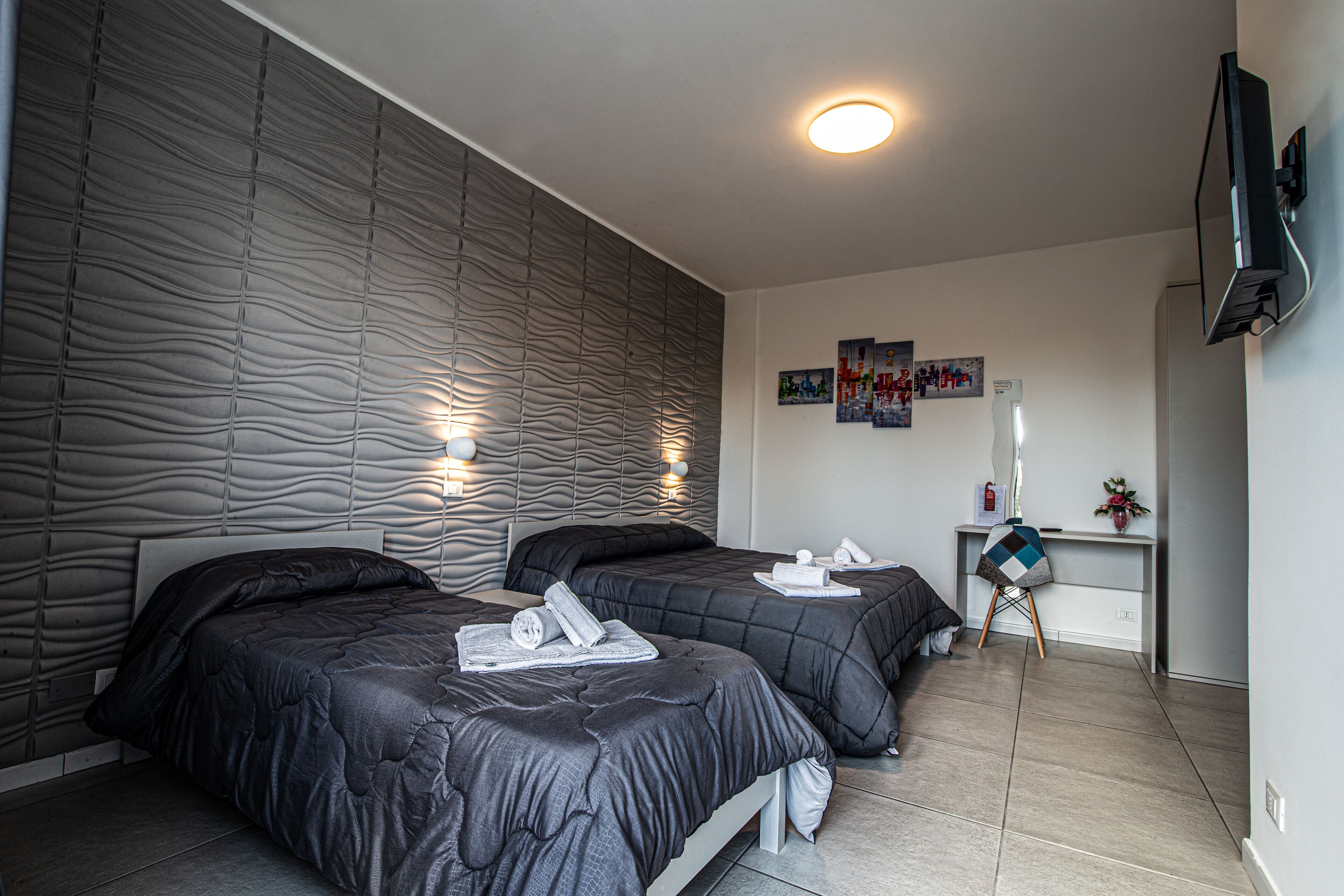 Une chambre d’hôtel moderne équipée de deux lits, d’un bureau et d’une télévision.