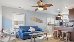 Una sala de estar moderna con un sofá azul, una mesa de centro de madera y un ventilador de techo.