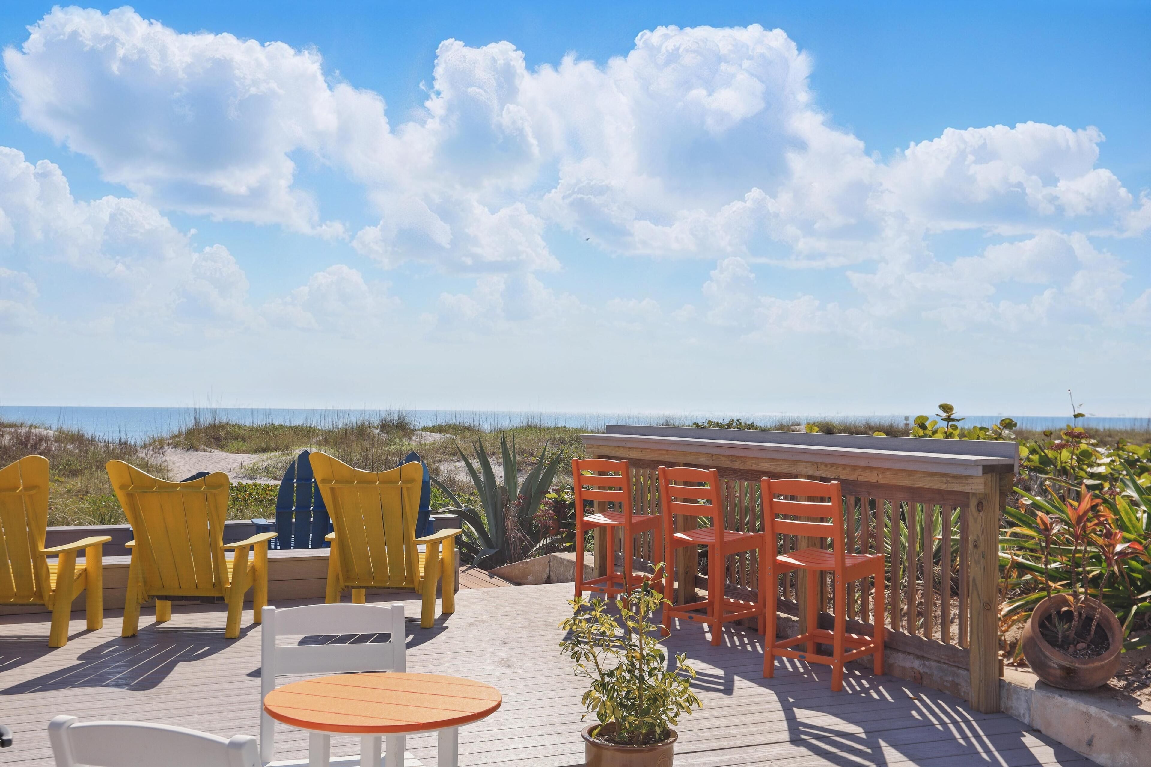 Una terraza de madera con mobiliario exterior y vistas a la playa.