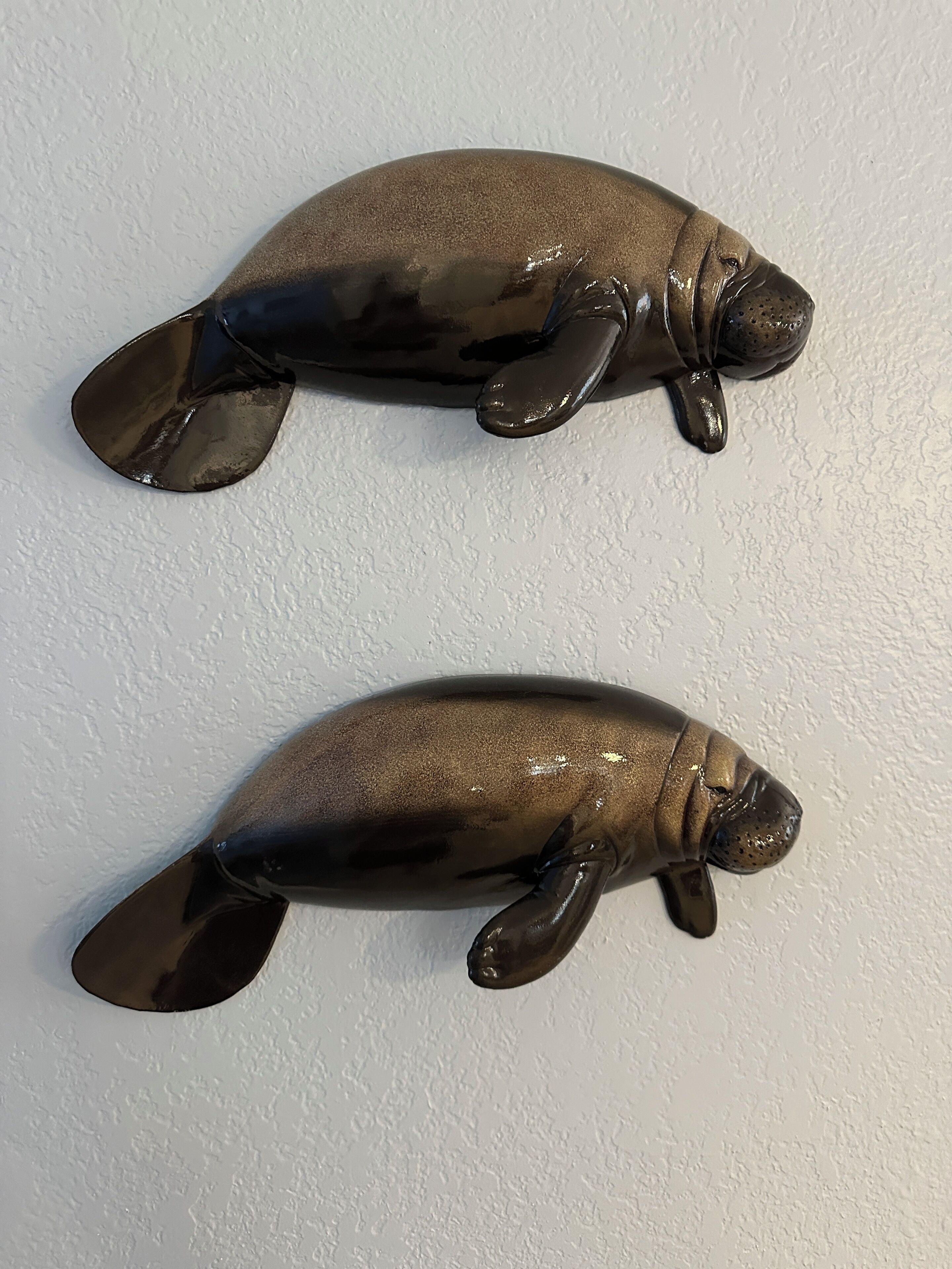 Dos figuras decorativas de peces montadas en la pared.
