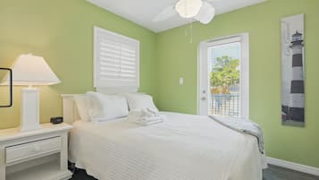 Un dormitorio con cama, mesita de noche, lámpara y ventilador de techo.