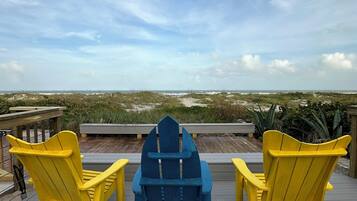 A deck with three Adirondack chairs facing a scenic view.