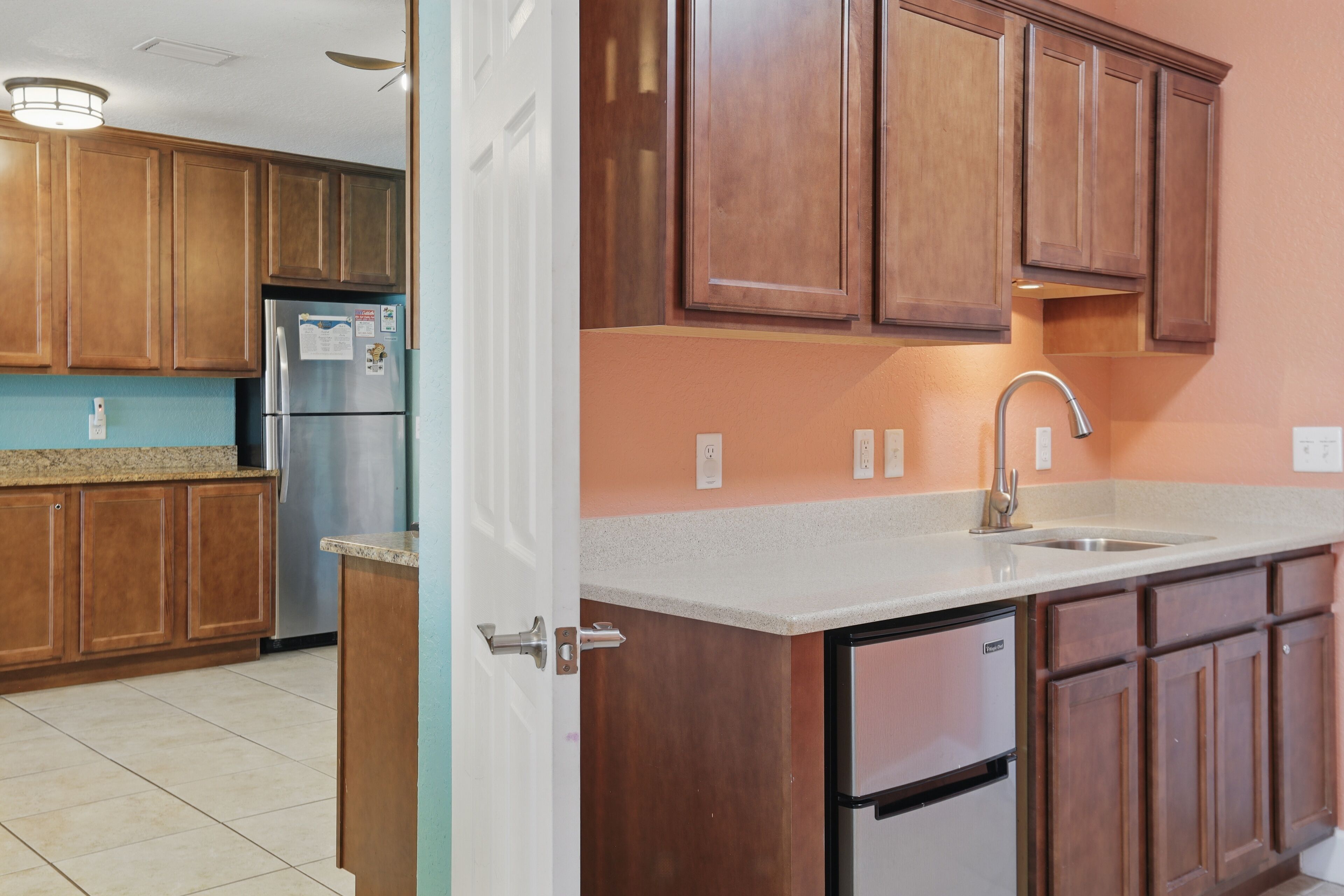 A kitchen with wooden cabinets, a stainless steel refrigerator, and a sink.