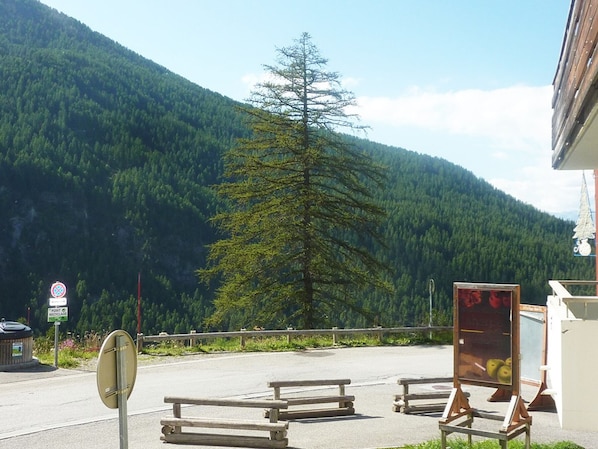 A parking area with picnic tables and a recycling sign, surrounded by a forested mountain.