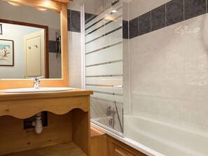 A bathroom with a wooden vanity, a glass shower enclosure, and a white bathtub. - Cozy 2-Room Apartment for 8 with Heated Pool, Sauna, and Mountain Views at Les Orres 1800 (Les Orres)
