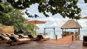 A wooden deck with lounge chairs and a thatched-roof structure overlooking the sea. - Zelune Luxury Lagoon Resort Bacalar Adults only (Bacalar)