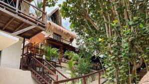 A multi-story building with a wooden staircase and thatched roof structures. - Zelune Luxury Lagoon Resort Bacalar Adults only (Bacalar)