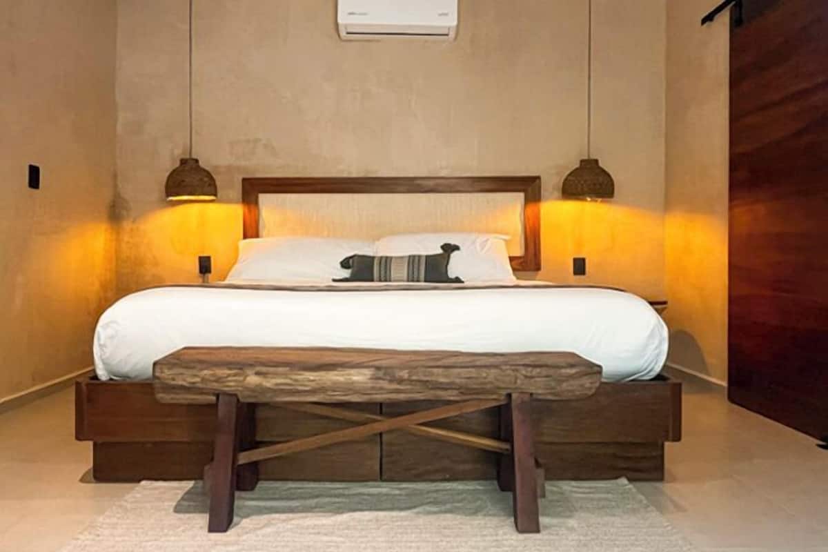 A bed with a wooden headboard, two bedside lamps, and a bench in front.
