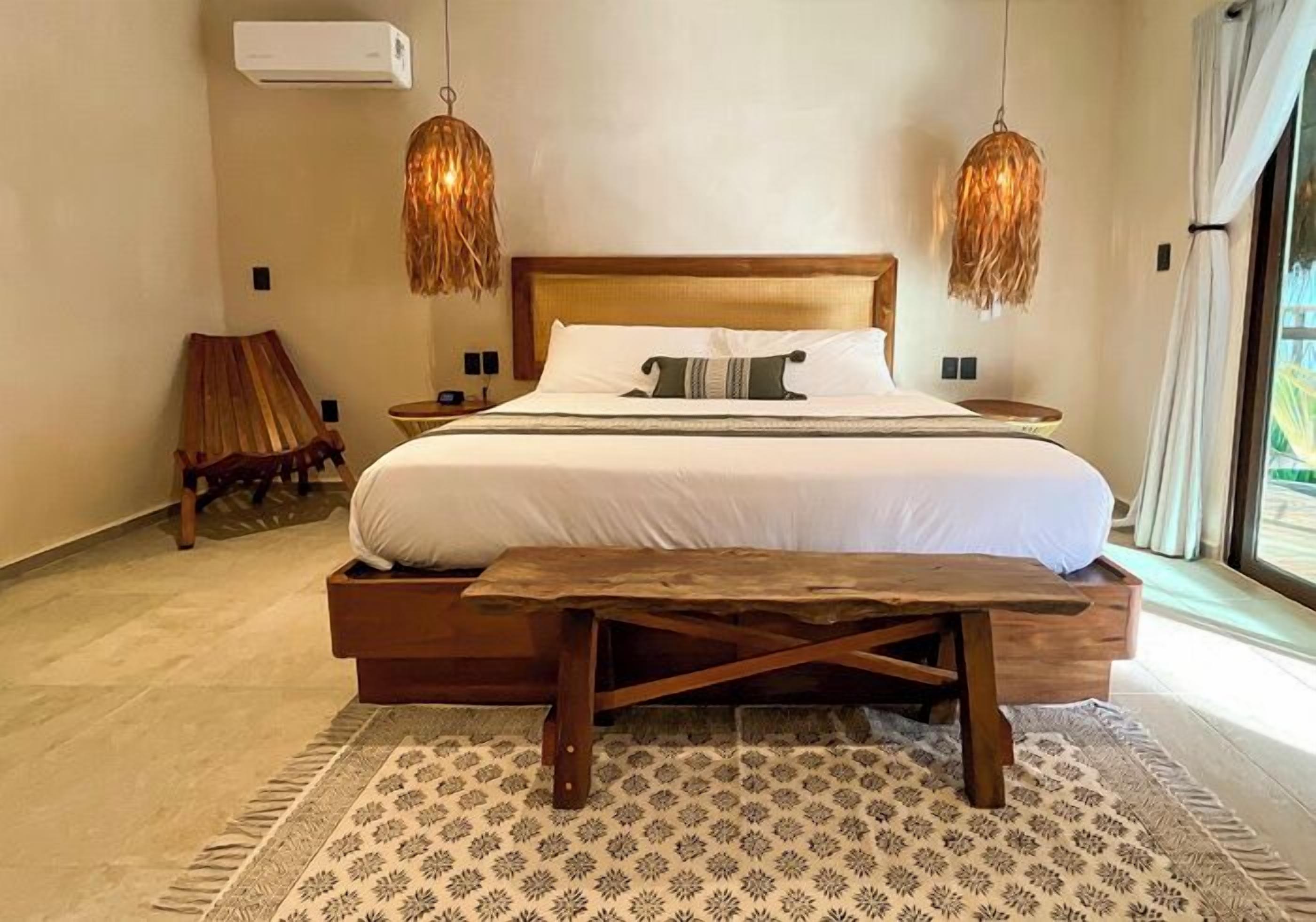 A spacious bedroom with a large bed, wooden headboard, and two hanging light fixtures.
