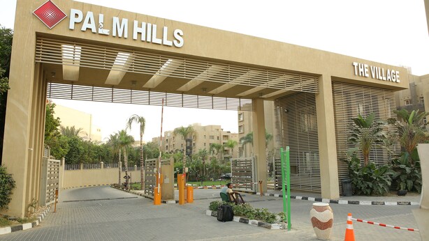 A gated entrance to Palm Hills with a sign for The Village.
