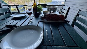 Ruokapöytä, jossa on kaksi paikkaa, ja josta avautuu näkymä satamaan ja vuorille.