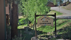 A sign for Racquet Club Commons with a natural, wooded background.