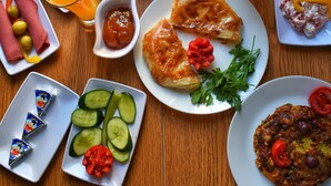 Ein Tisch mit verschiedenen Frühstücksangeboten, darunter Brot, Obst, Gemüse und Beilagen.