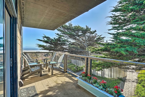 A balcony with a view of the ocean, a wooden deck, and a railing.