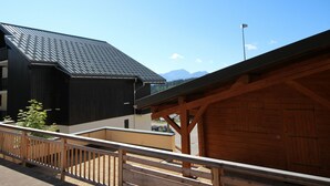 Ein modernes Gebäude mit dunkler Fassade und geneigtem Dach, neben einer Holzhütte mit einer großen Garagentür.