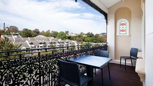 A balcony with a table and chairs, a decorative railing, and a stained glass window.