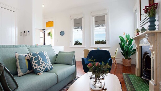 A living room with a sofa, armchair, coffee table, and a fireplace.