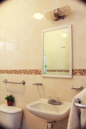 Un baño con inodoro, lavamanos y espejo.