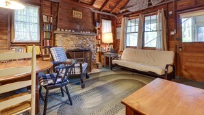 L’intérieur d’un chalet chaleureux, avec une cheminée en pierre, des meubles en bois et un fauteuil à carreaux.