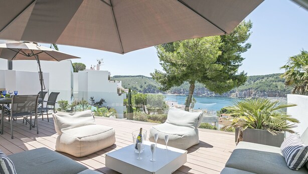 A deck with outdoor furniture, a table with glasses, and a view of the sea. - Noelia: Exclusive villa overlooking the sea and private pool. (L'Escala)