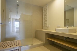 Ein modernes Badezimmer mit einer Duschkabine aus Glas, einem integrierten Waschbecken und einem großen Spiegel.