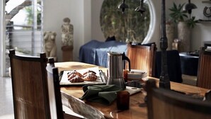 A dining area with a wooden table, chairs, a coffee pot, and pastries. - Haven Oceana (Emerald Beach)