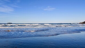 A beach with waves, a clear sky, and a distant island. - Haven Oceana (Emerald Beach)