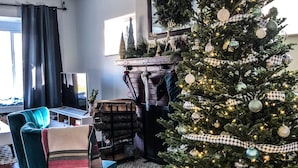 A living room with a fireplace, a Christmas tree, a teal armchair, and a television. - 6 Bedroom/4.5 Bath/Across from Motown Museum (Detroit)