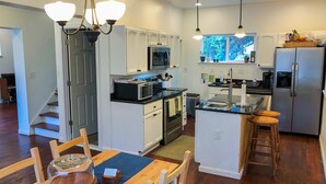 A modern kitchen with white cabinetry, stainless steel appliances, and a central island with stools. - 6 Bedroom/4.5 Bath/Across from Motown Museum (Detroit)