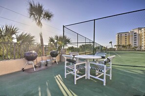 An outdoor patio with a barbecue setup, a table, and chairs. - Beachfront Resort Condo w/ Panoramic Ocean Views! (New Smyrna Beach)
