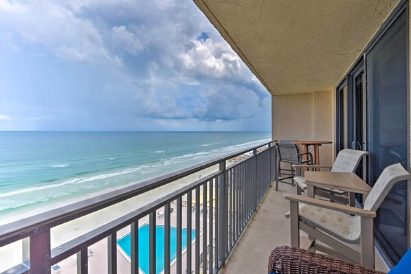 A balcony with a view of the ocean, a pool, and outdoor seating. - Beachfront Resort Condo w/ Panoramic Ocean Views! (New Smyrna Beach)