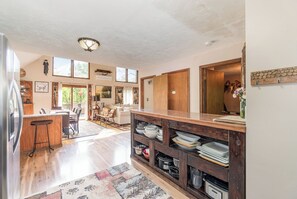 Enjoy meals in the kitchen with a sink and bar stools, connected to a dining area with a large table and chairs.