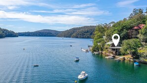 A lake with boats, a house with a red roof, and a large tree. - The Deckhouse, Cottage Point. Waterfront Adults Retreat. (Cottage Point)