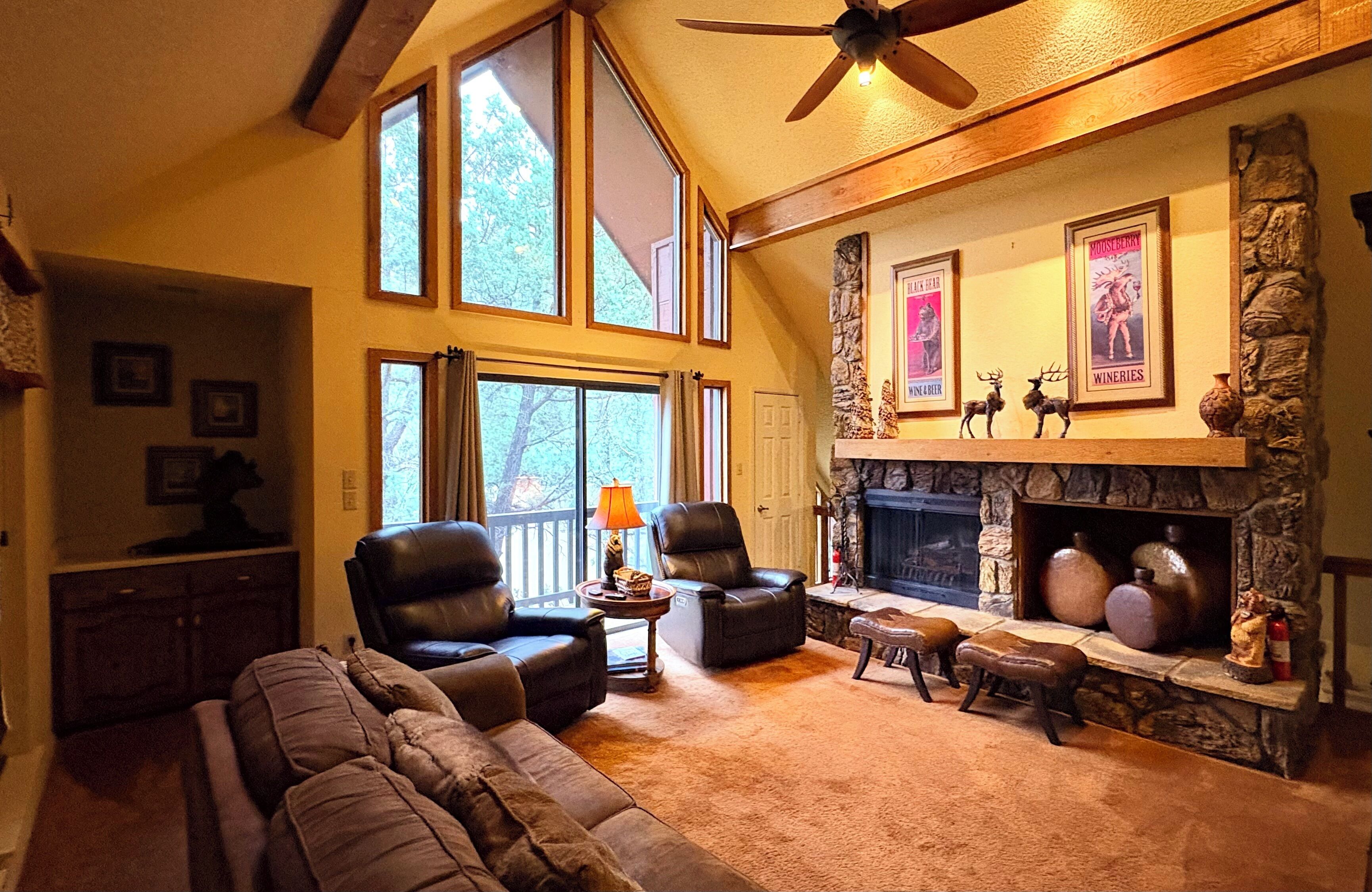 A spacious living room with a fireplace, leather sofas, and a stone accent wall.