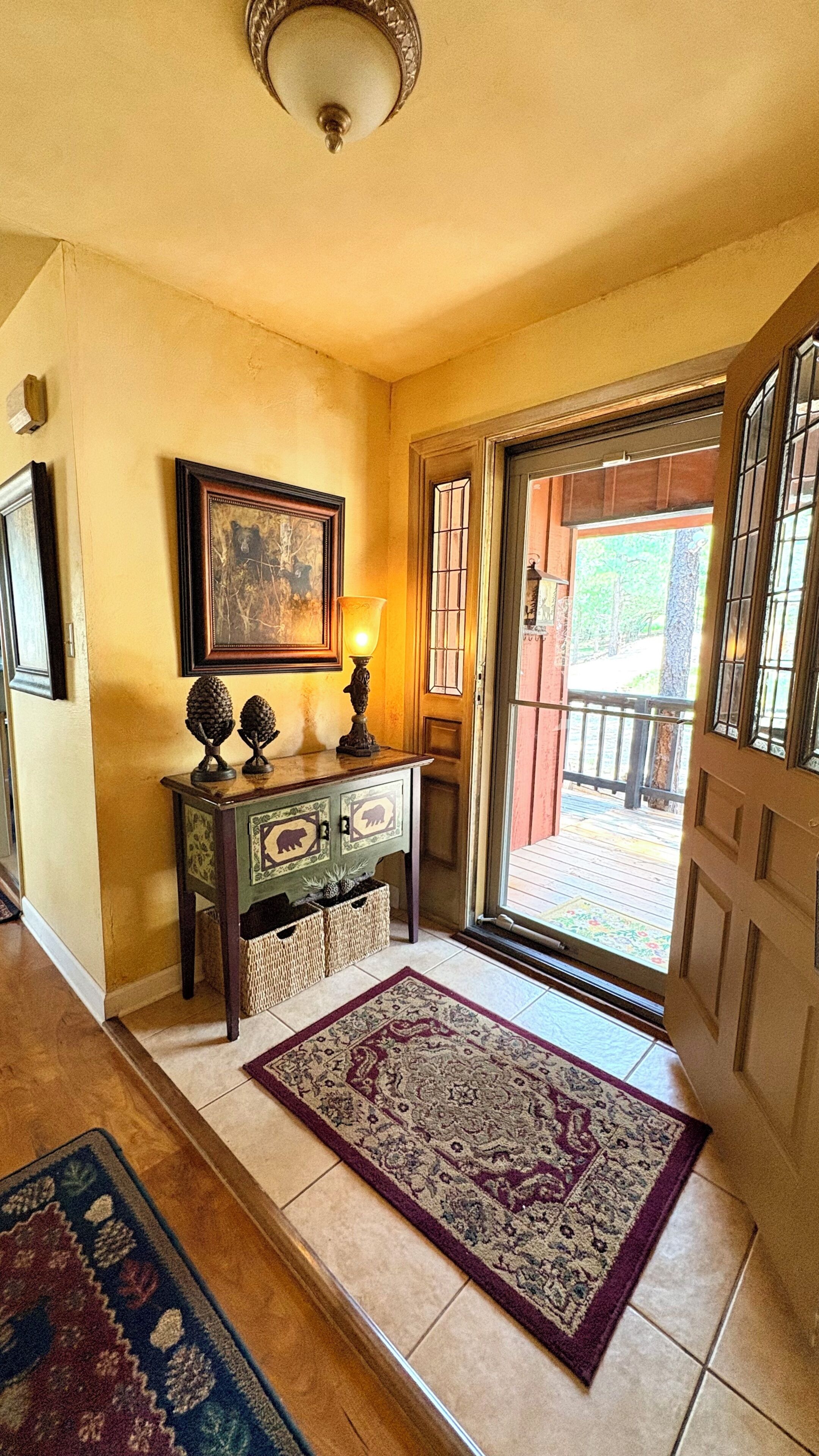 A hallway with a wooden console table, a rug, a framed picture, and a door leading to an outdoor area.