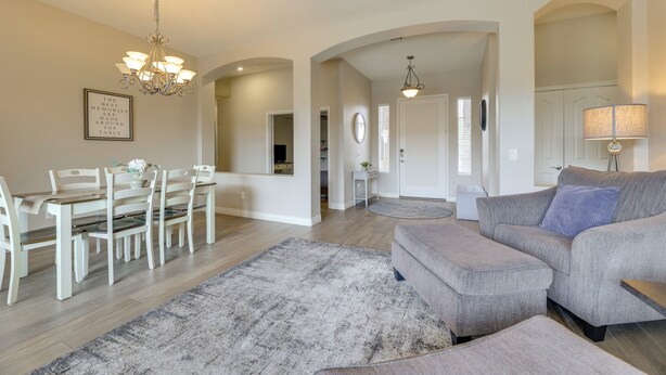 A spacious living room with a grey sofa, a dining table with chairs, and a chandelier. - 4 Mi to Riparian Preserve: Mesa Abode w/ Hot Tub (Mesa)