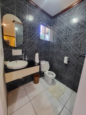 A bathroom with a sink, toilet, and mirror.