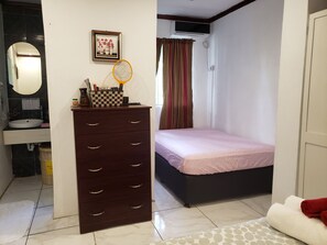 A bedroom with a bed, a dresser, a sink, and an air conditioning unit.