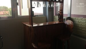 Eine Bar mit Holztresen, hängenden Weingläsern und einer Statue.
