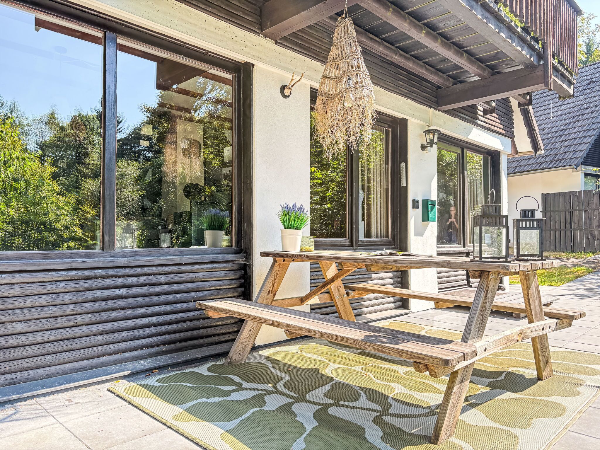 A wooden deck with a picnic table, potted plants, and a hanging light fixture.