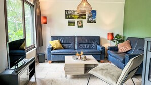 Ein modernes Wohnzimmer mit einem blauen Sofa, einem Couchtisch und einem Fernseher auf einem Lowboard.