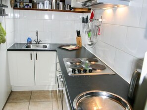 Et moderne køkken med hvide skabe, en sort bordplade, en gaskomfur og en stålvask.